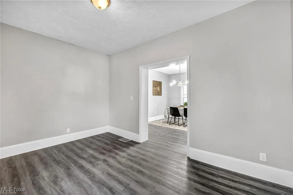 Unfurnished room featuring dark wood finished floors, a textured ceiling, and a chandelier