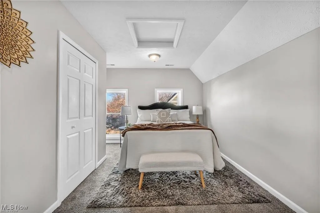 Carpeted bedroom featuring attic access and vaulted ceiling
