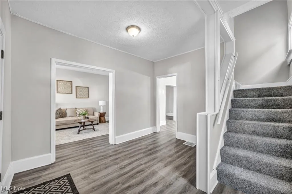 Entryway with stairs, wood finished floors, and a textured ceiling