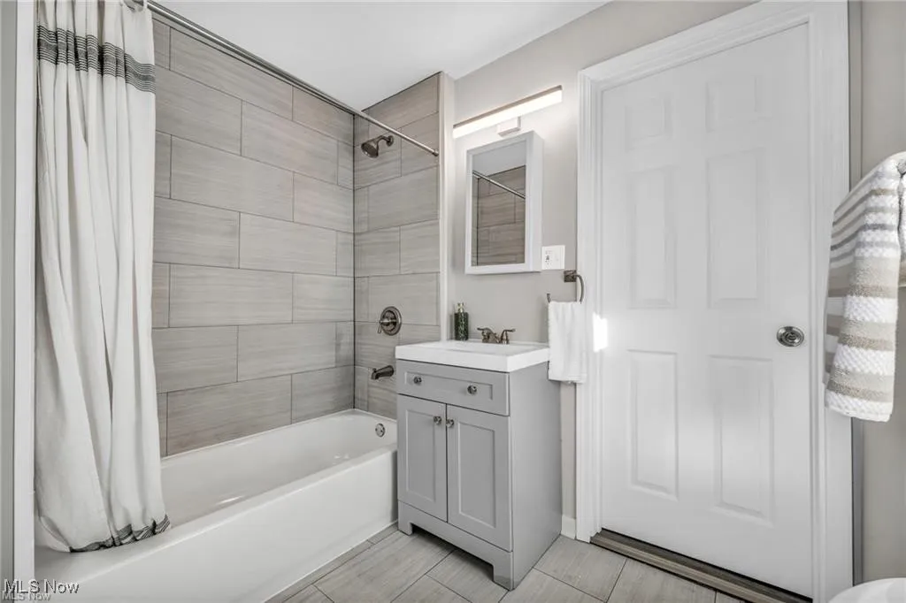 Full bath with shower / bath combo with shower curtain and vanity
