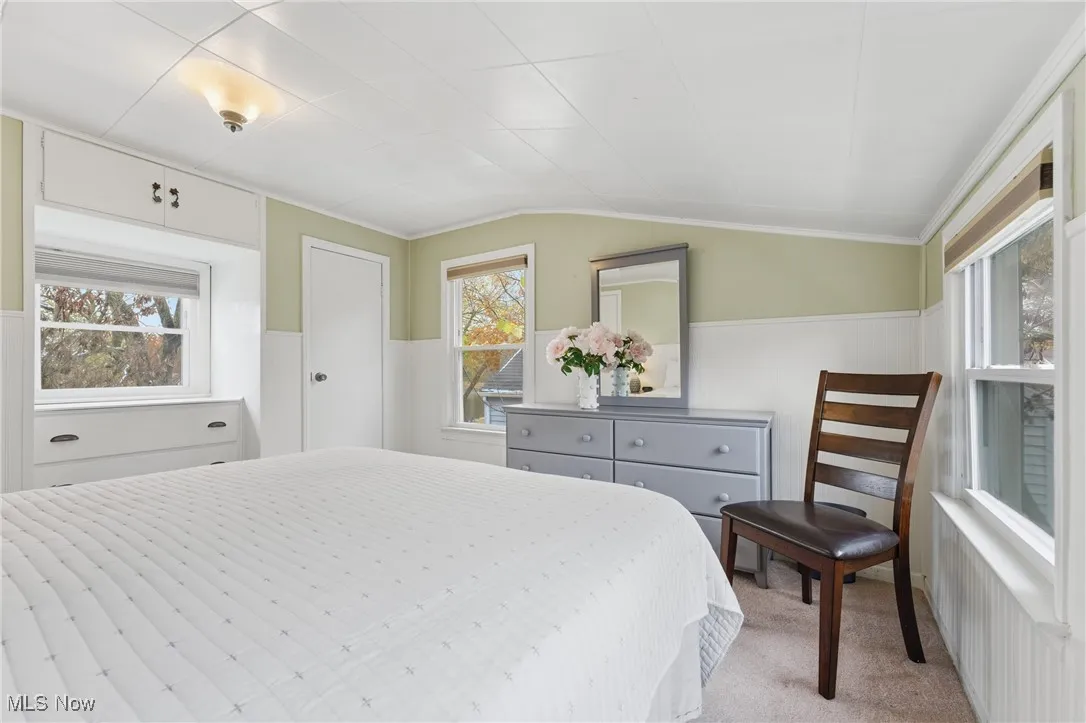 Carpeted bedroom featuring wainscoting