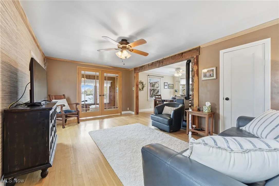 Living area featuring light wood finished floors, french doors, a ceiling fan, and ornamental molding