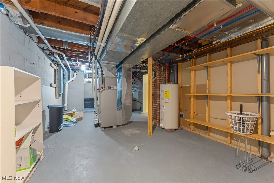 Unfinished below grade area with heating unit and electric water heater