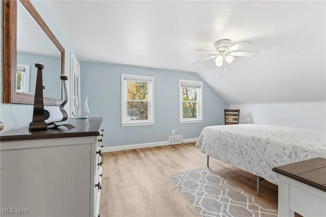 Bedroom with light wood-type flooring, lofted ceiling, and a ceiling fan