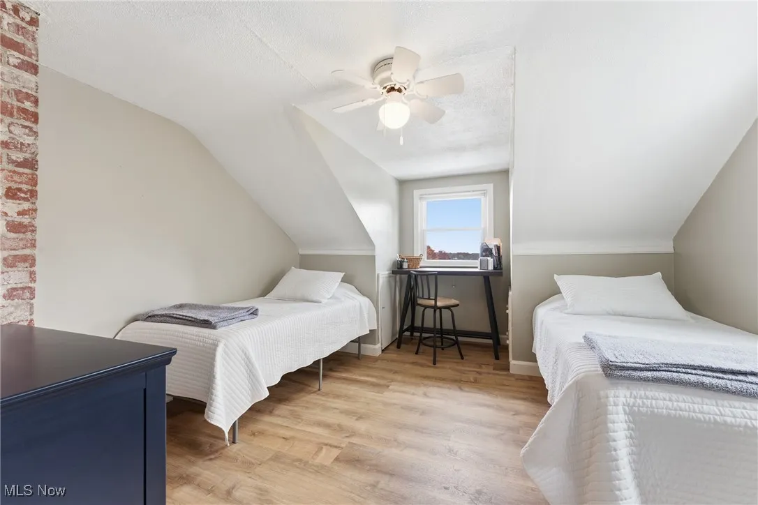 Bedroom with light wood-style flooring, a ceiling fan, a textured ceiling, and vaulted ceiling