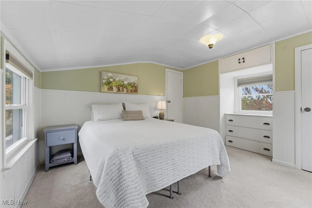 Carpeted bedroom featuring wainscoting and vaulted ceiling