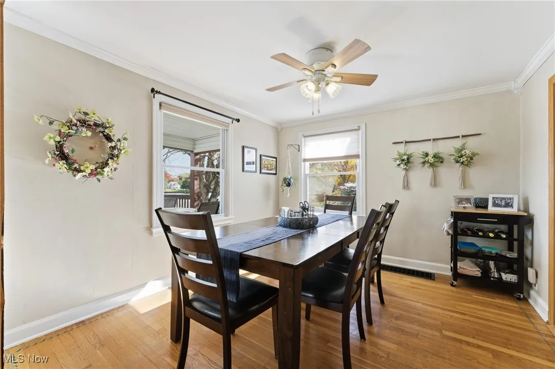 Dining area with light wood-type flooring, ornamental molding, and a ceiling fan