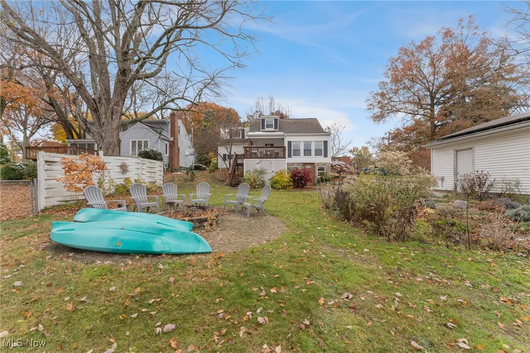 Back of house featuring an outdoor fire pit, a lawn, a patio, and a balcony
