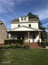 Back of property with covered porch and a lawn