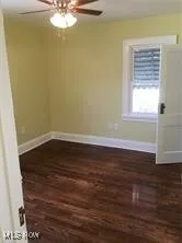 Unfurnished room with dark wood finished floors and ceiling fan