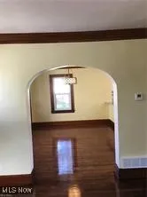 Bonus room with arched walkways and dark wood-type flooring