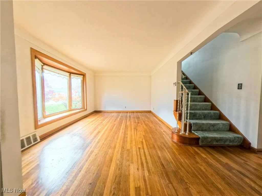 Unfurnished living room with hardwood / wood-style floors and stairs