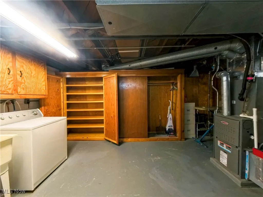 Unfinished below grade area with washer / clothes dryer and heating unit