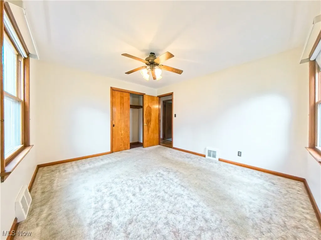 Unfurnished bedroom with multiple windows, carpet flooring, a closet, and ceiling fan