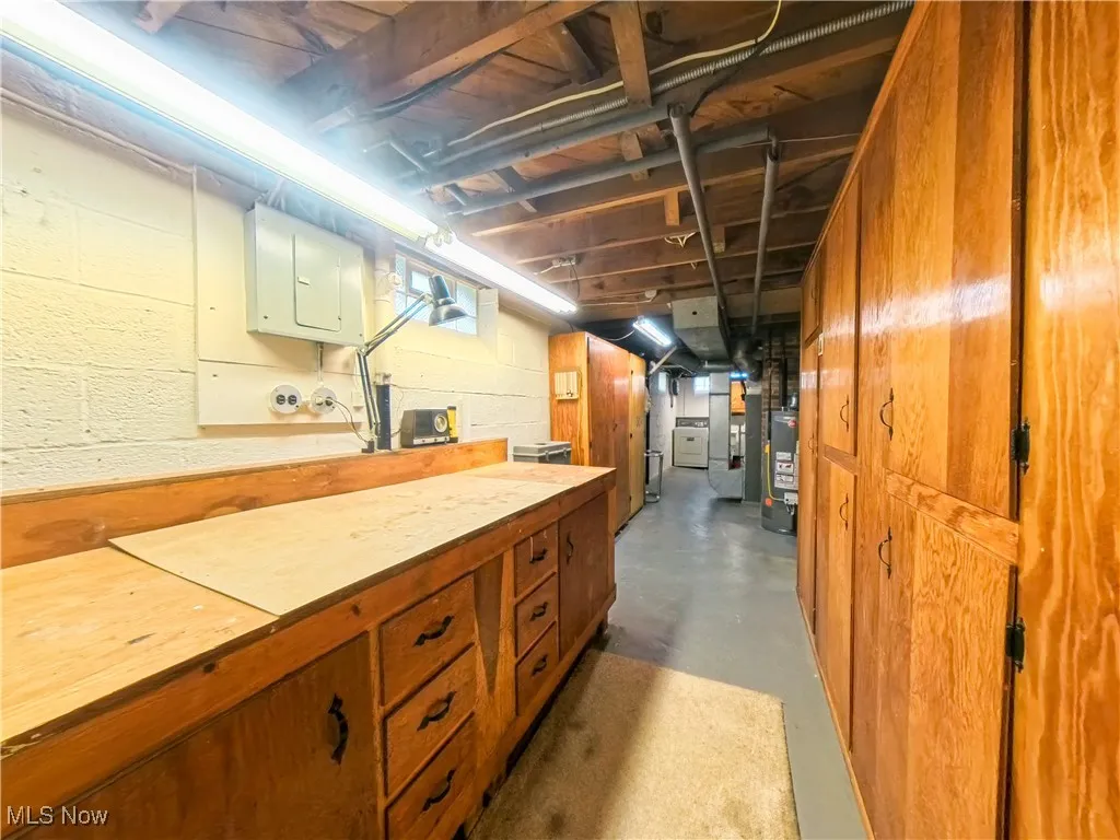 Unfinished basement featuring washer / clothes dryer and water heater