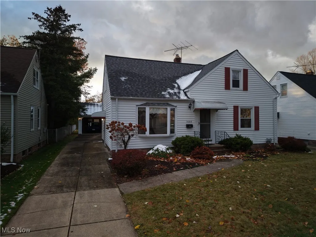 View of front of home featuring a front yard, a chimney, a shingled roof, and a garage