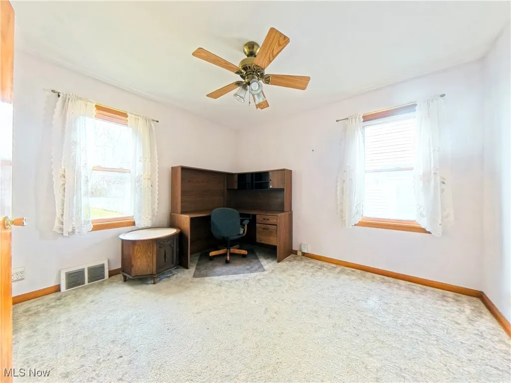 Office space featuring light colored carpet, plenty of natural light, and a ceiling fan