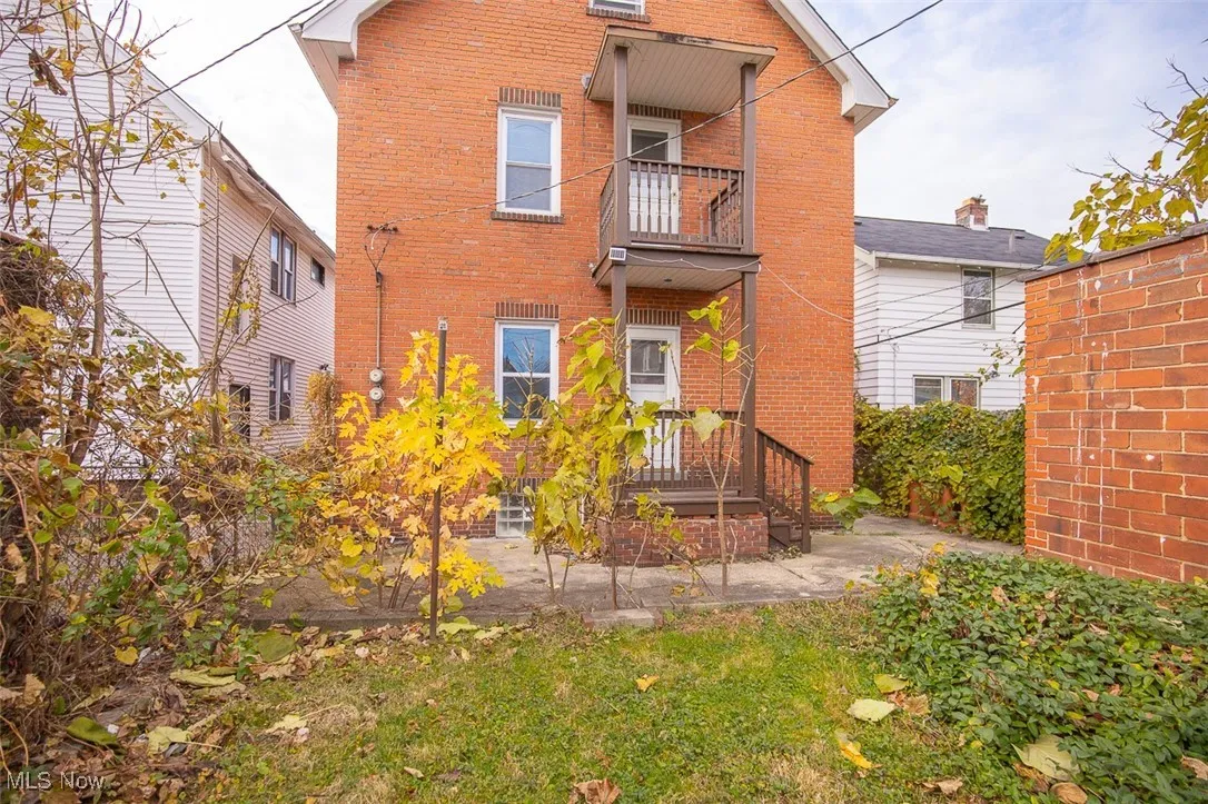 Rear view of house featuring brick siding, a patio, and a balcony