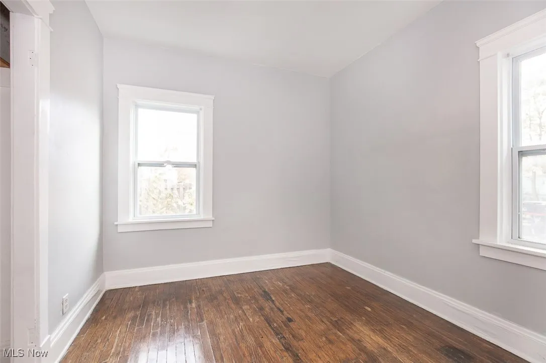 Empty room featuring dark wood-style flooring and baseboards