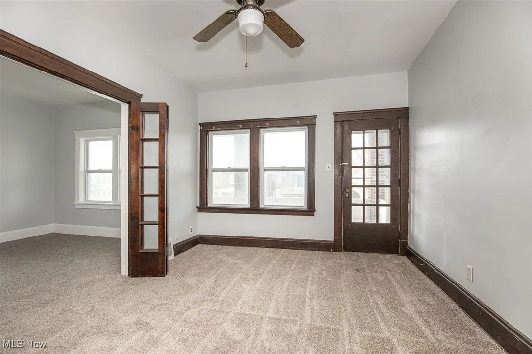 Empty room featuring light carpet, plenty of natural light, and a ceiling fan