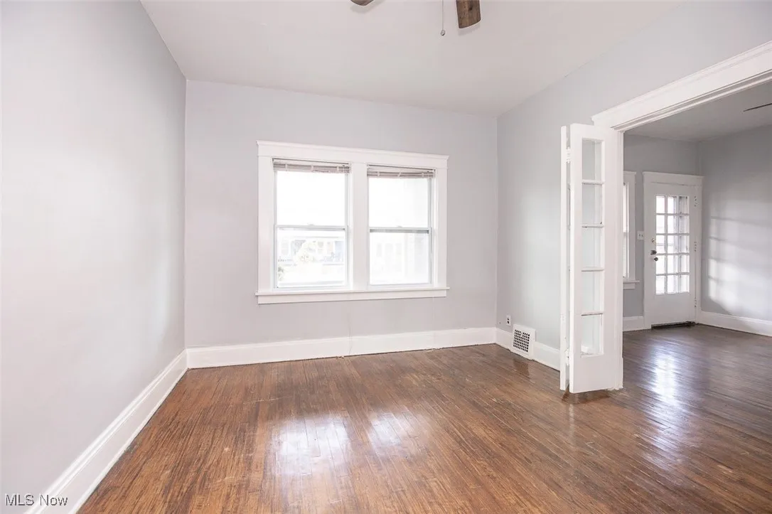 Empty room featuring dark wood finished floors, ceiling fan, and french doors