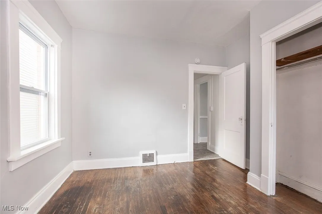 Unfurnished bedroom featuring dark wood-type flooring and baseboards