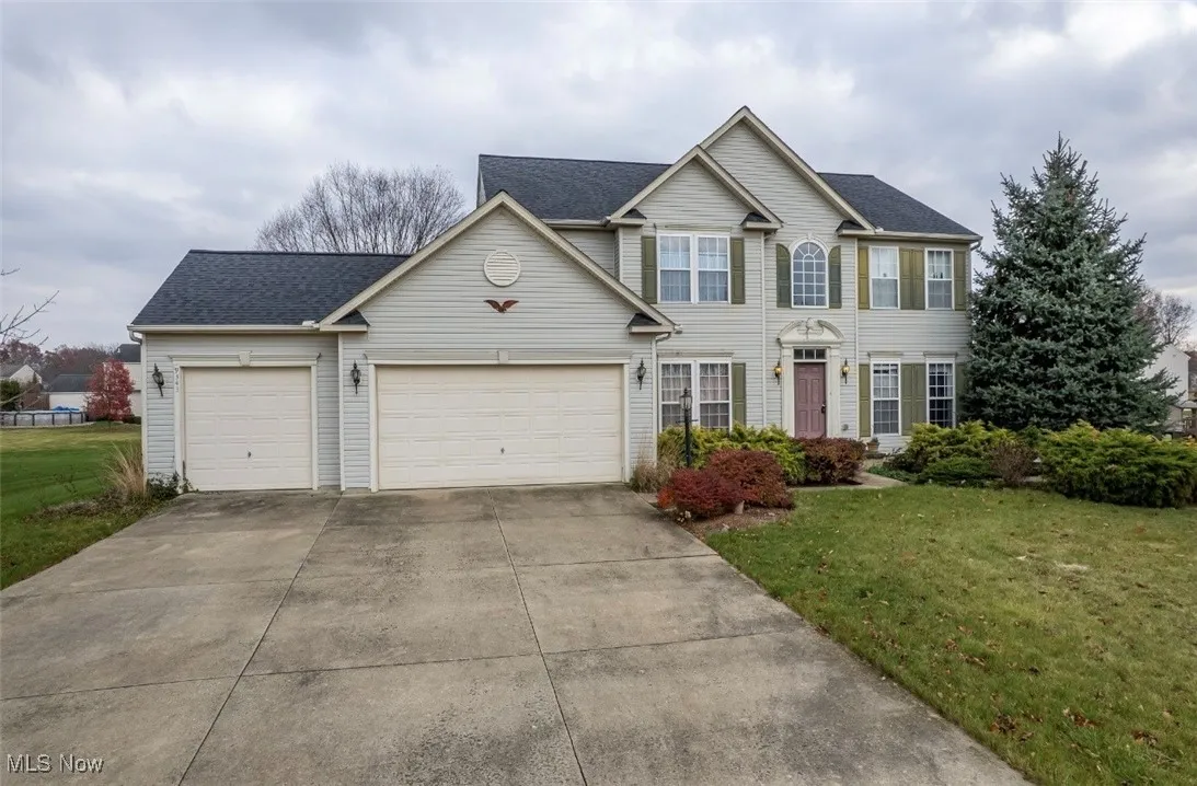 View of front of home with a front lawn, concrete driveway, an attached garage, and roof with shingles