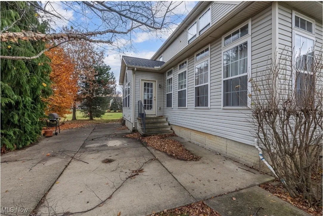 View of side of home with a patio, entry steps, and a shingled roof