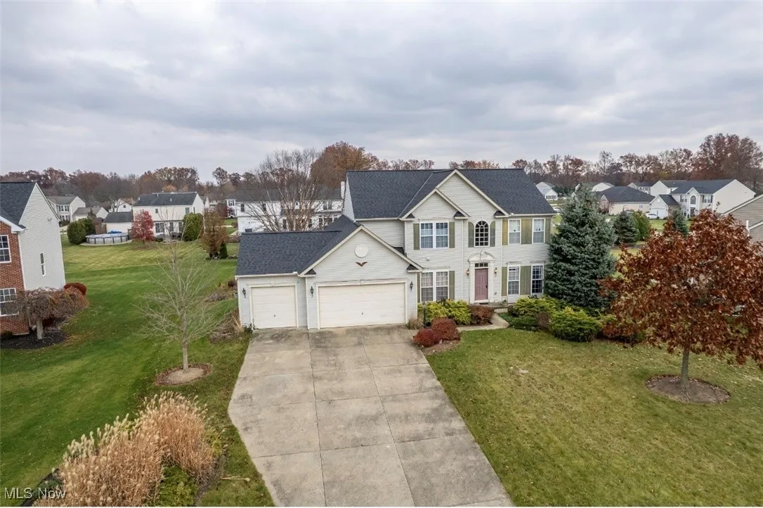 View of front of property with a front lawn, an attached garage, driveway, and a residential view
