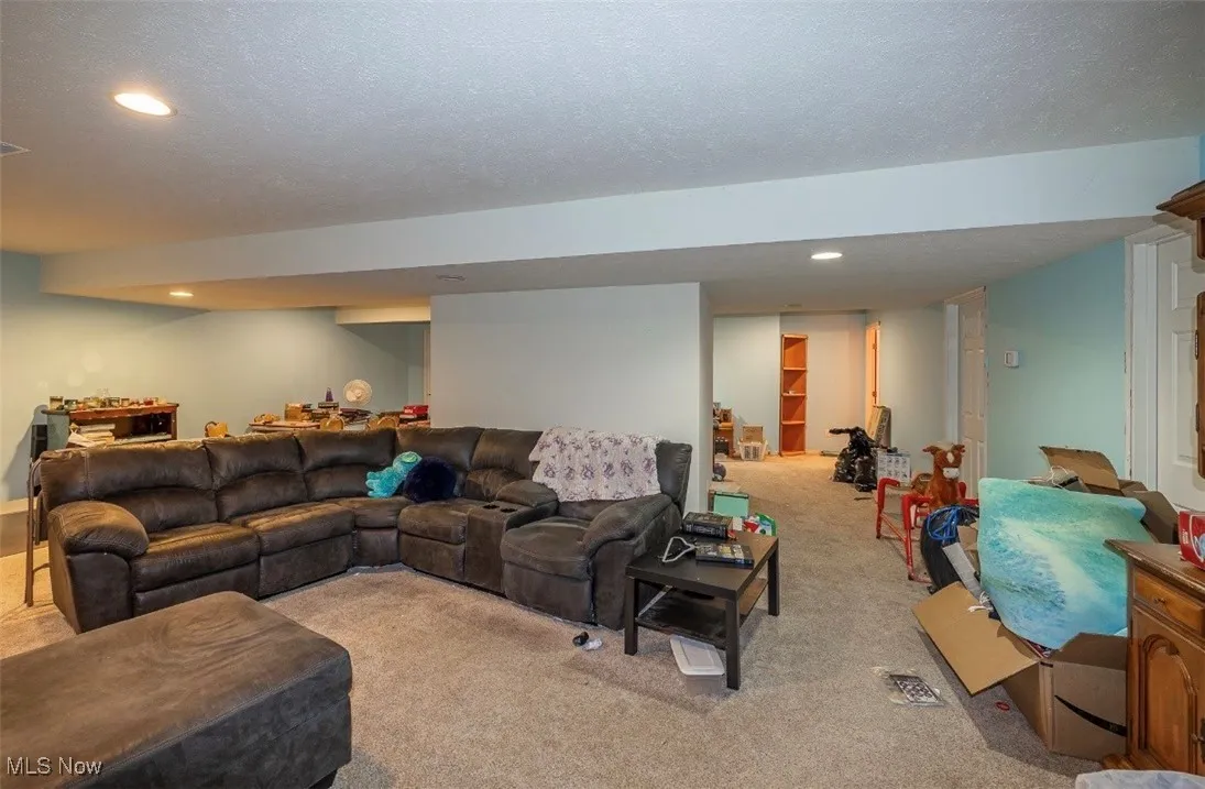 Living area with light colored carpet, recessed lighting, and a textured ceiling