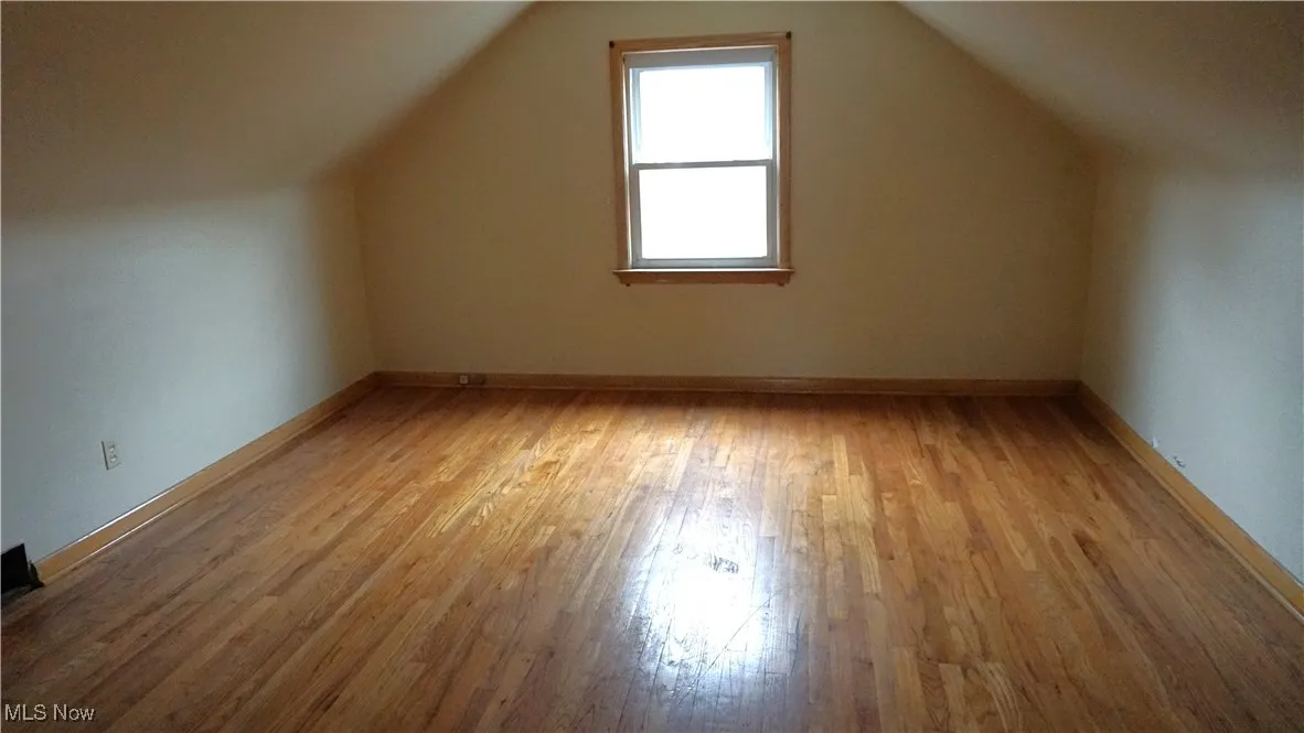 Bonus room with light wood flooring and lofted ceiling