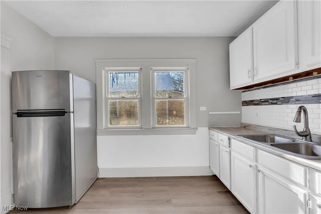 Kitchen with freestanding refrigerator, white cabinets, light wood finished floors, and light countertops
