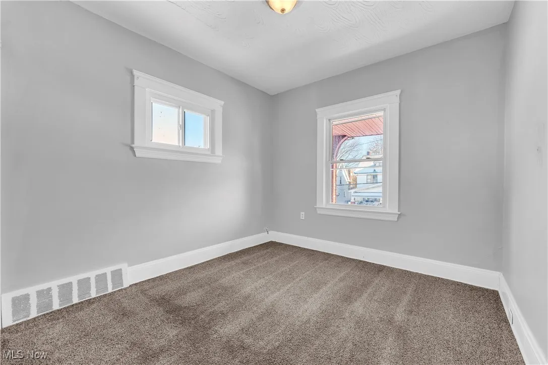 Carpeted spare room featuring baseboards