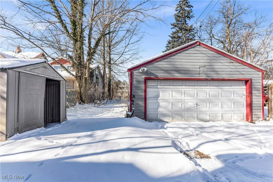 Snow covered garage with a detached garage and a shed
