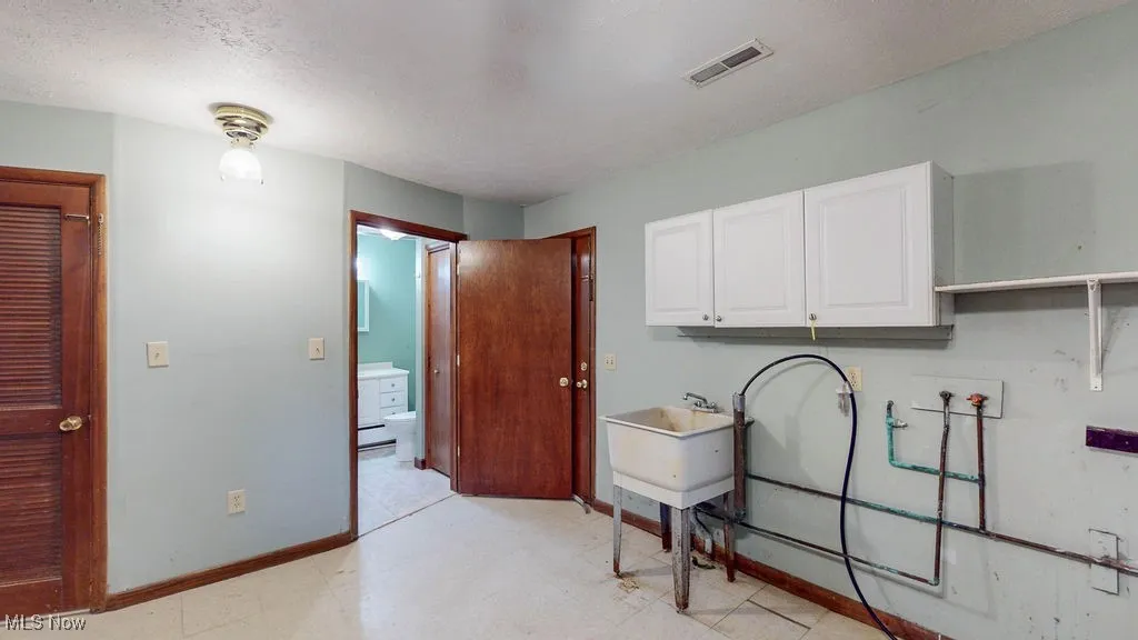 Laundry area with light flooring, washer hookup, and cabinet space