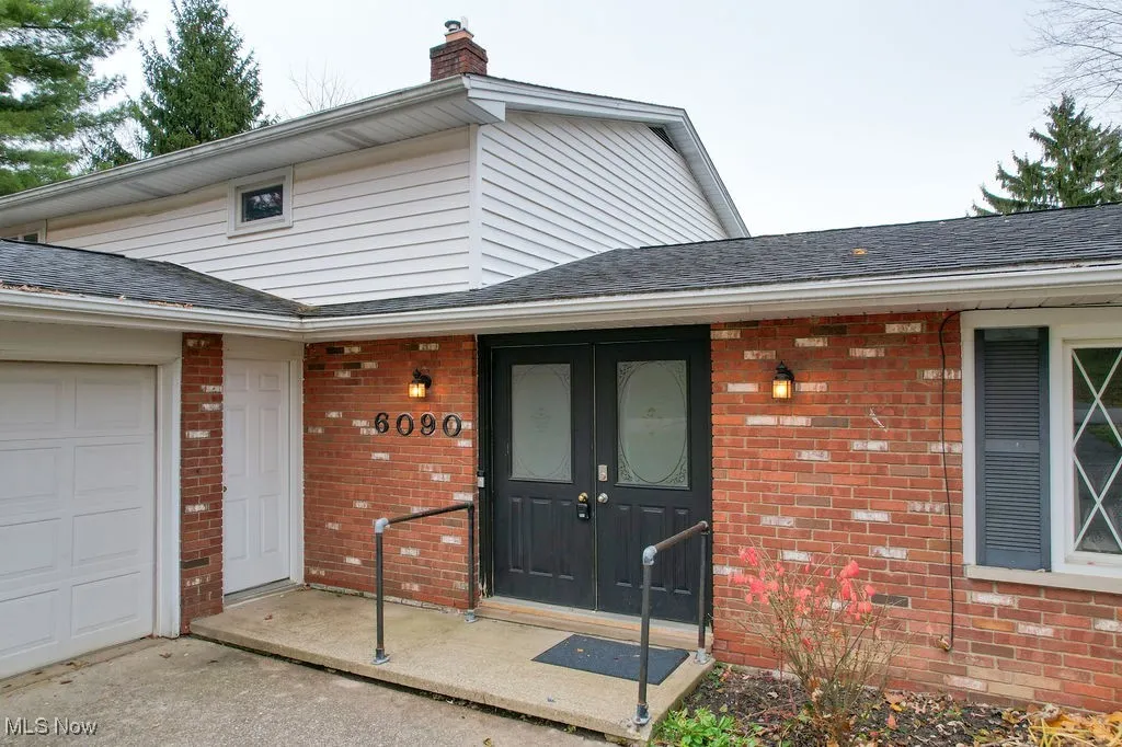 Entrance to property with brick siding, roof with shingles, and a chimney