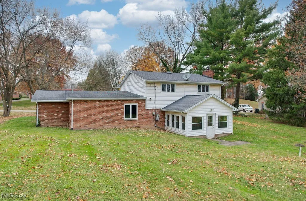 Back of house featuring a lawn and brick siding