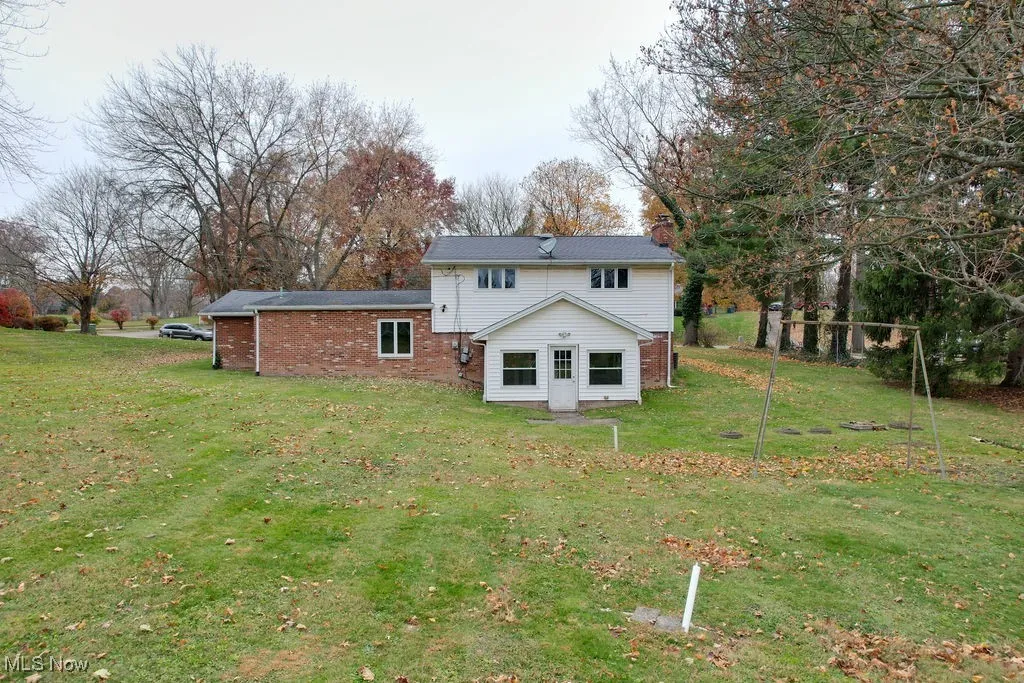 Back of house featuring a yard and brick siding
