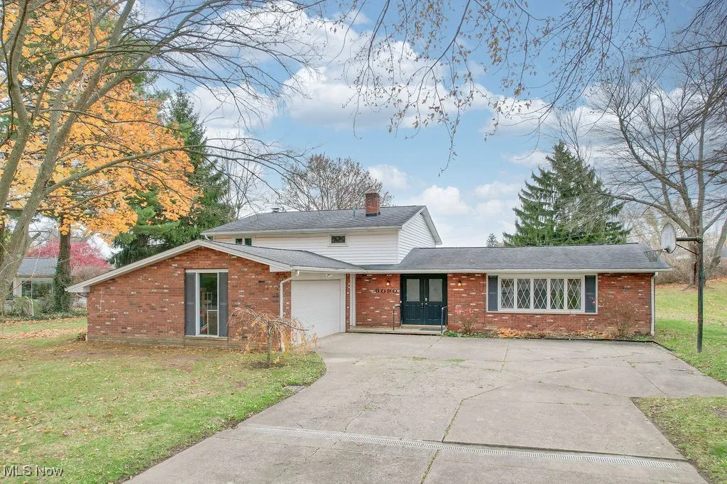 View of front of property featuring a front yard, brick siding, driveway, and a garage