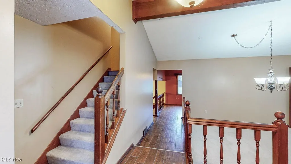 Stairs featuring wood finished floors and a chandelier
