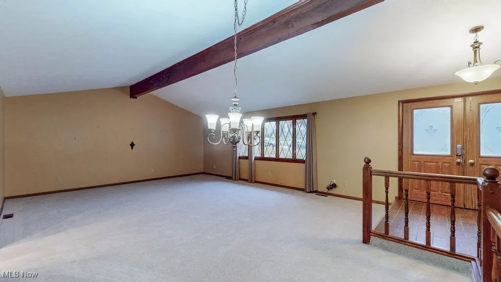 Unfurnished dining area and living room featuring light colored carpet and a chandelier