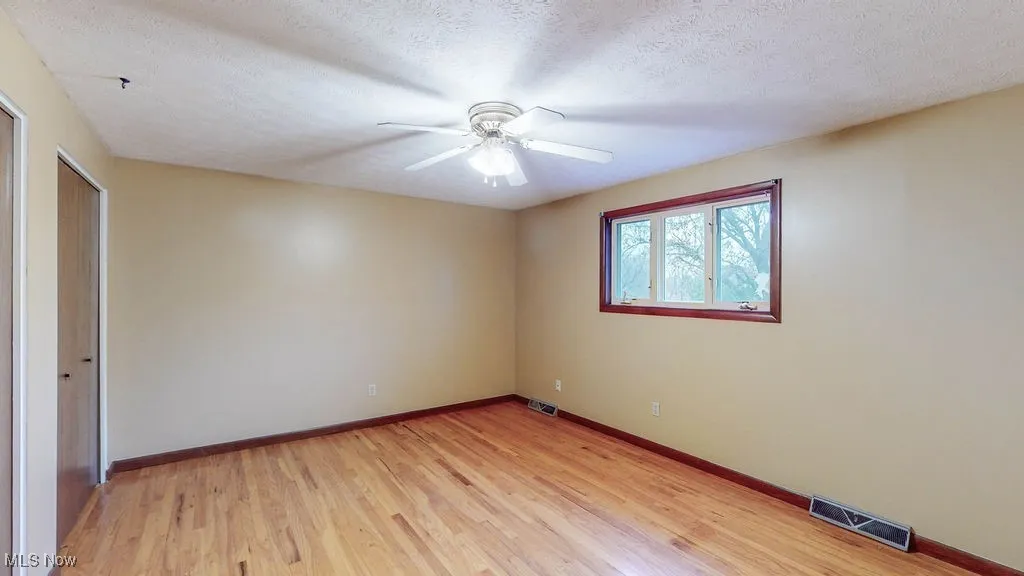 Unfurnished bedroom featuring light wood-type flooring, a textured ceiling, and a ceiling fan