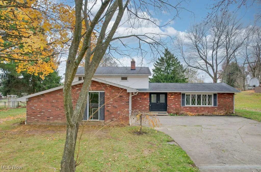 View of front facade with a front lawn, brick siding, a chimney, and driveway