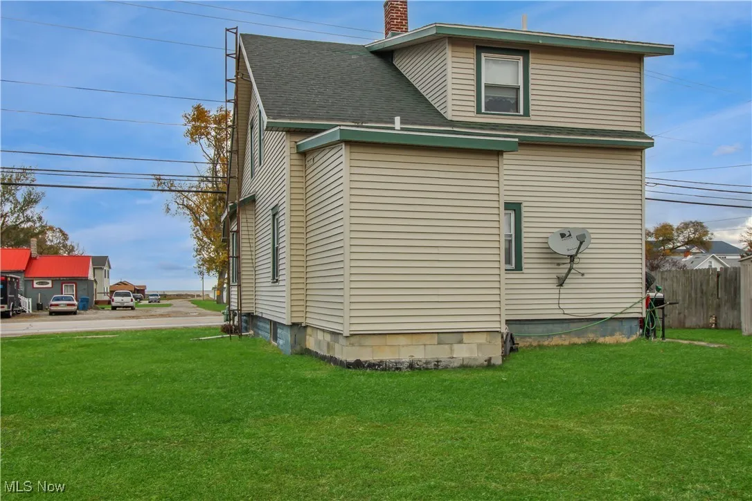View of side of property with a chimney and roof with shingles