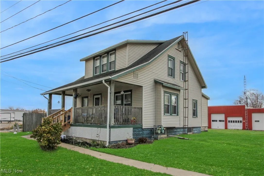 View of property exterior with a yard, covered porch, an outbuilding, and a detached garage