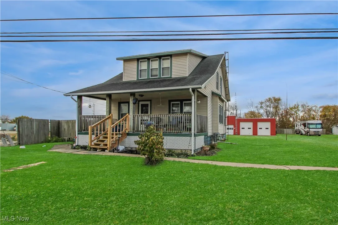 Bungalow-style home featuring a porch, a shingled roof, an outdoor structure, and a garage
