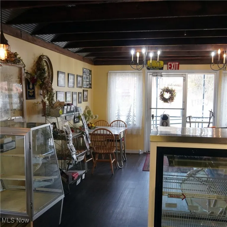 Dining area featuring a chandelier, dark wood finished floors, and beam ceiling