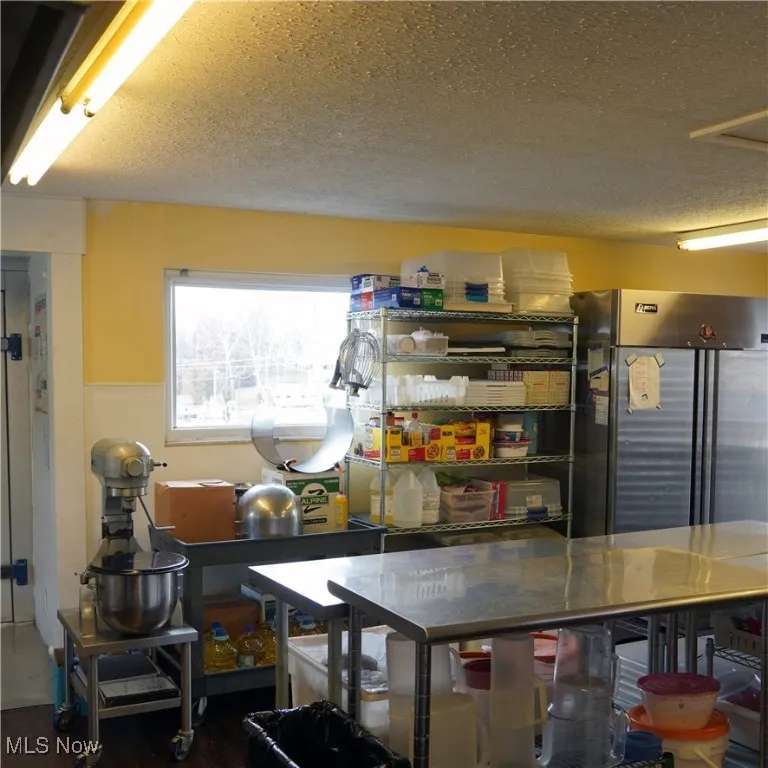 Kitchen featuring stainless steel refrigerator and a textured ceiling