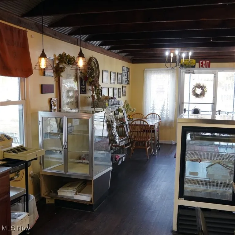 Dining space with dark wood finished floors and beamed ceiling