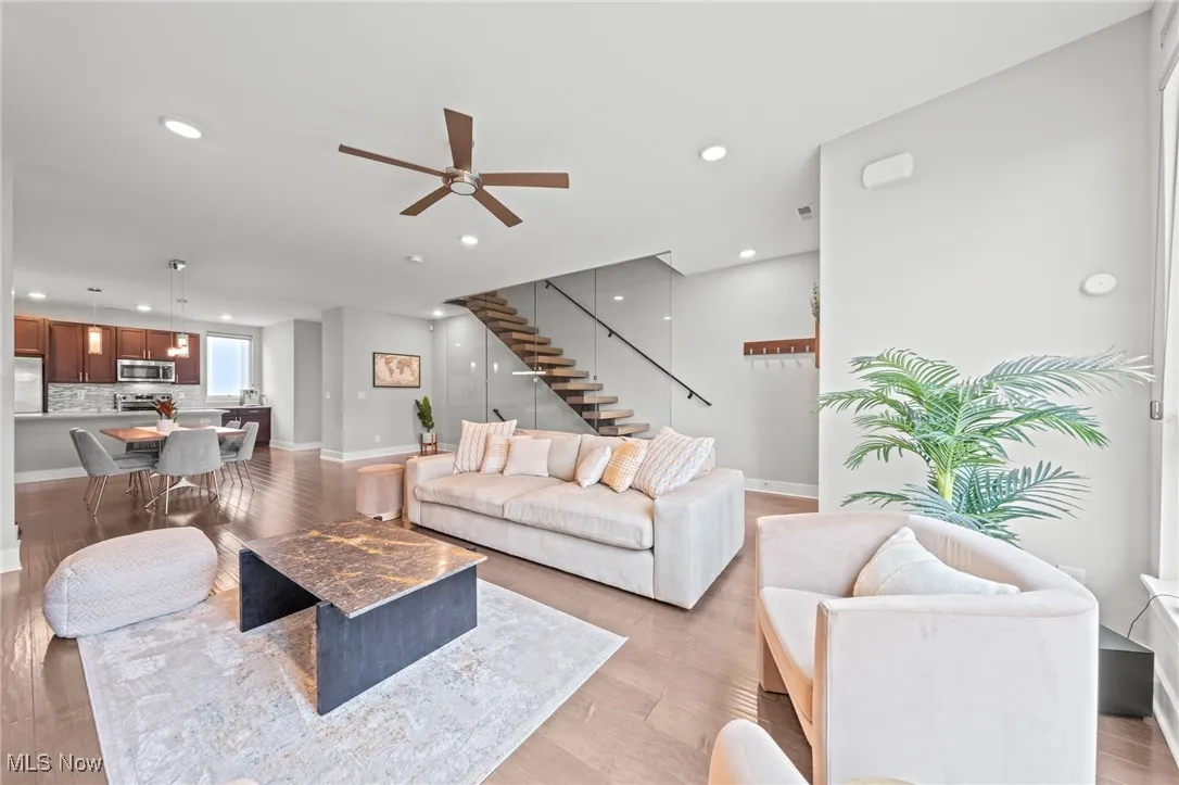 Living room featuring light wood finished floors, recessed lighting, a ceiling fan, and stairs